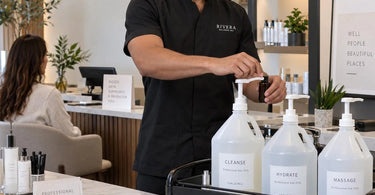 Professional spa backbar setup with pump dispensers and organized caddies to reduce lifting and improve ergonomics for salon and spa professionals