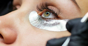 A close-up of a woman receiving a lash tint treatment in a spa setting