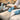 Close-up of a spa professional cleaning and conditioning the smooth vinyl surface of a modern massage table in a well-lit treatment room.