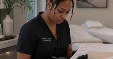 A professional spa aesthetician carefully applying lash and brow tint to a client in a serene coastal spa setting.