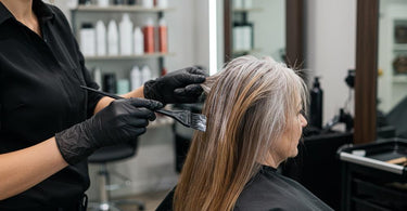 Professional hair stylist applying color to cover gray hair in a salon setting