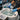 A close-up view of a spa professional's hands cleaning the jets of a white whirlpool pedicure spa with a blue brush, with cleaning supplies visible nearby.