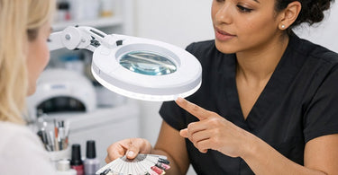 Nail artist using a magnifying lamp for precision nail art detailing on a client at a professional nail station