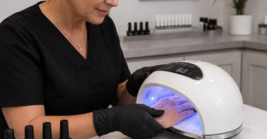 Close-up of a professional nail technician applying a high-pigment black gel polish to a client's nails, highlighting the rich pigment and glossy finish.