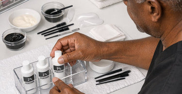 Professional lash tinting supplies including various peroxide developers and mixing tools arranged on a salon workspace