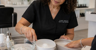 Variety of ceramic, glass, and plastic finger soaking bowls displayed on a spa counter with towels and cuticle oil nearby