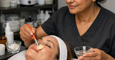Close up of a professional synthetic fan brush used for safe and even glycolic acid application on a client's face in a spa setting.