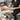 Professional esthetician working on a client in a spa treatment room while seated on a modern adjustable hydraulic stool, demonstrating proper posture and ergonomic equipment use.