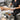 Professional esthetician working on a client in a spa treatment room while seated on a modern adjustable hydraulic stool, demonstrating proper posture and ergonomic equipment use.