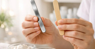 Close-up comparison of a single-use bamboo spatula and a reusable metal spatula on a spa towel, highlighting hygiene choices for professionals.