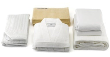 Spa Linens Starter Kit from Pure Spa Direct featuring a stack of high-quality white towels and sheets for professional salon and spa use.