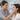 A beauty professional smiling during a consultation with a client, holding a color swatch near the client's face to demonstrate a strategic compliment in action.