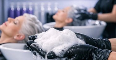 A selection of professional salon-grade purple shampoo bottles for platinum blonde and gray hair, displayed on a marble spa background