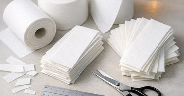 An assortment of different types of professional wax strips including non-woven, woven, and plastic strips, displayed on a light background, illustrating the complete guide to wax strips for salons and spas.