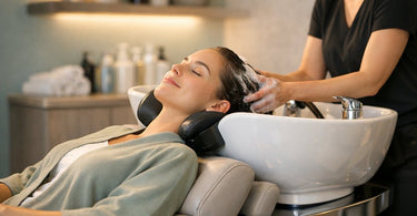 A stylist comfortably washing a client's hair at an ergonomic shampoo station, demonstrating proper posture and client support.