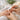 Close-up view of a professional nail technician performing precise cuticle work during a manicure preparation.