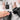 A professional nail technician's hands applying builder gel to a client's natural nail, with bottles of soft gel, hard gel, and BIAB in the background.