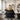 A professional hairstylist holding a large presentation mirror behind a client's chair to show the client the back of their new haircut in a bright, modern salon.