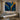 A close-up of a single, striking abstract painting with textured blue and gold tones, representing the transformative power of art in a spa or salon environment.