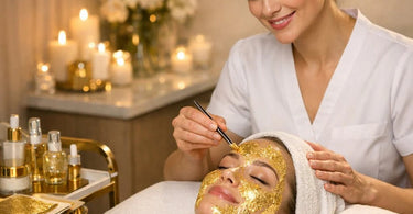Close-up of a professional esthetician applying delicate gold leaf sheets during a luxurious anti-aging facial treatment in a spa setting