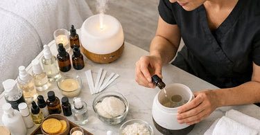 A curated collection of aromatherapy essential oils and a modern diffuser displayed on a wooden tray with a closed eye model evoking the psychology of scent in a spa environment.