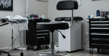 Professional tattoo artist working while sitting on an ergonomic hydraulic stool in a modern studio