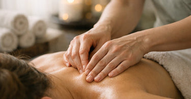 A massage therapist's hands applying targeted pressure to a client's shoulder to release a muscle knot