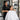 A professional salon cape being held with care, symbolizing cleanliness and client comfort.