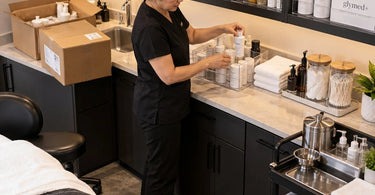 Professional salon backbar being organized with supplies removed from cardboard shipping boxes and placed into clean permanent storage