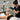A professional beauty therapist smiling and preparing to take a before photo of a client in a clean, well-lit salon, emphasizing the importance of a dedicated lighting setup for client photos.