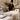 Professional esthetician arranging plush linens and a warming pad on a facial table in a spa treatment room