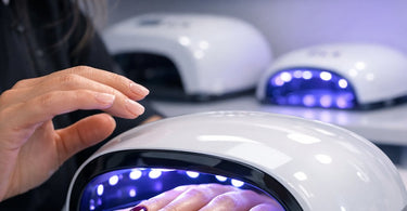 A close-up of a professional nail lamp shining on a perfectly manicured hand with gel polish, illustrating proper curing technique for salons.
