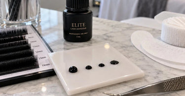 Professional lash adhesive drops changing shape on a glue tile during an eyelash extension service
