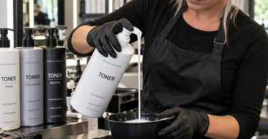Professional toner bottle with controlled dispensing cap on a spa backbar surrounded by skincare products and cotton pads
