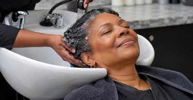 A stylist gently washing a client's hair in a modern, comfortable shampoo bowl at a professional salon, highlighting the relaxing and ergonomic experience.