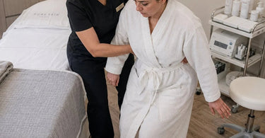 A professional spa staff member carefully and safely guiding a relaxed client from a massage table during an emergency drill, showcasing safe client handling.