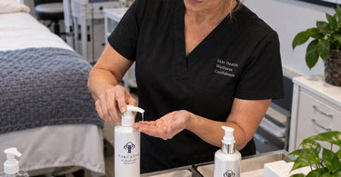 Spa staff member testing a product pump before handing a purchase to a client at a salon front desk