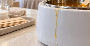 Professional spa waxing workstation with a wax warmer, melted wax residue around the base, wooden applicators, and waxing supplies illustrating why wax drips collect beneath the warmer