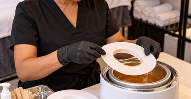Disposable wax pot collar protecting a professional wax warmer from drips and buildup at a salon station