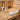 A close-up view of a spa professional's hands gently cleaning the warm, wooden interior of an infrared sauna with a soft cloth and a spray bottle of wood-safe cleaner.