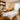 A neatly organized massage room featuring a dedicated draping station with stacked fluffy white towels and sheets on wooden shelves, a towel steamer, and a professional massage table prepared for a client, emphasizing spa organization and client comfort.