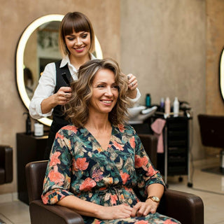 A stylist cutting a woman's hair in a salon, showcasing the perfect flattering length for over 50