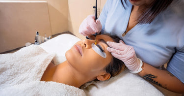 Woman receiving intensive lash tinting service at a spa
