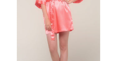 A professional spa model wearing the light coral Women's Satin Kimono Short Robe from Summa Ya, showcasing the elegant wrap style and 3/4 sleeves for a luxurious spa experience.